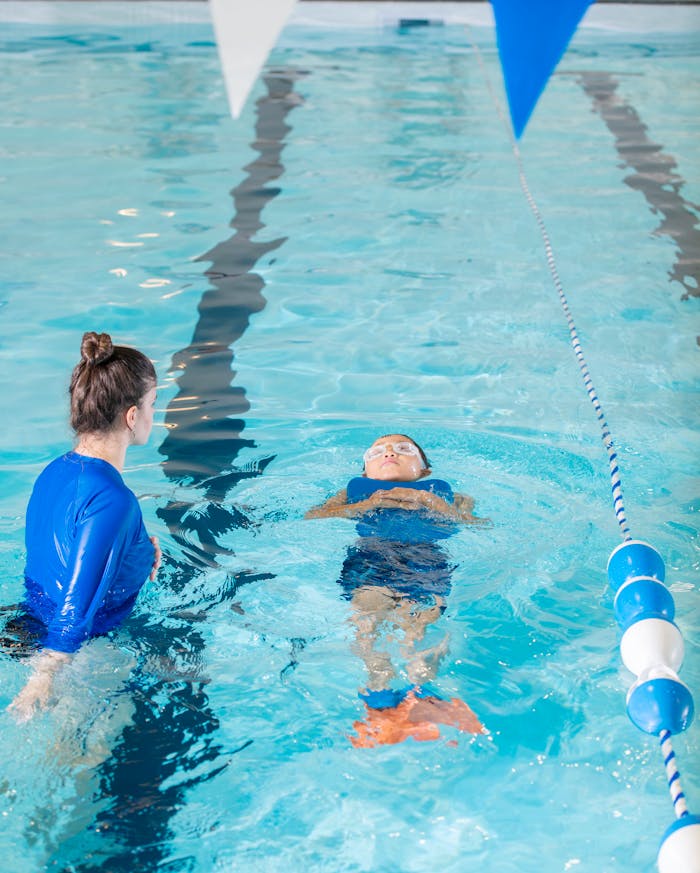 portfolio-03 A swimming instructor teaches a young child to swim in an indoor pool.