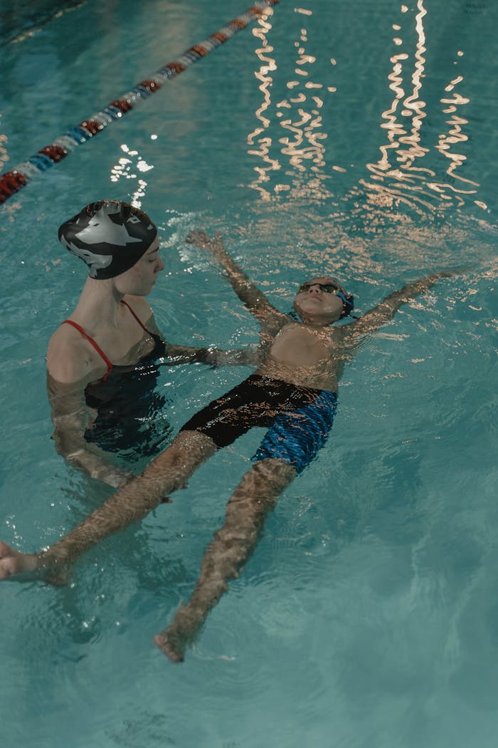 portfolio-02 A child learning to swim with the guidance of an instructor in an indoor swimming pool.