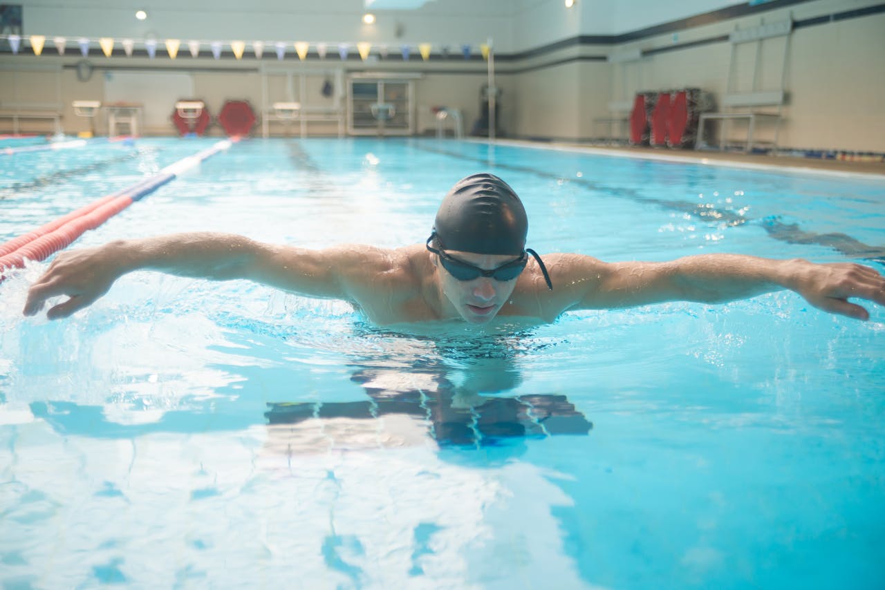 stats-img Focused male swimmer practicing butterfly stroke in an indoor swimming pool.